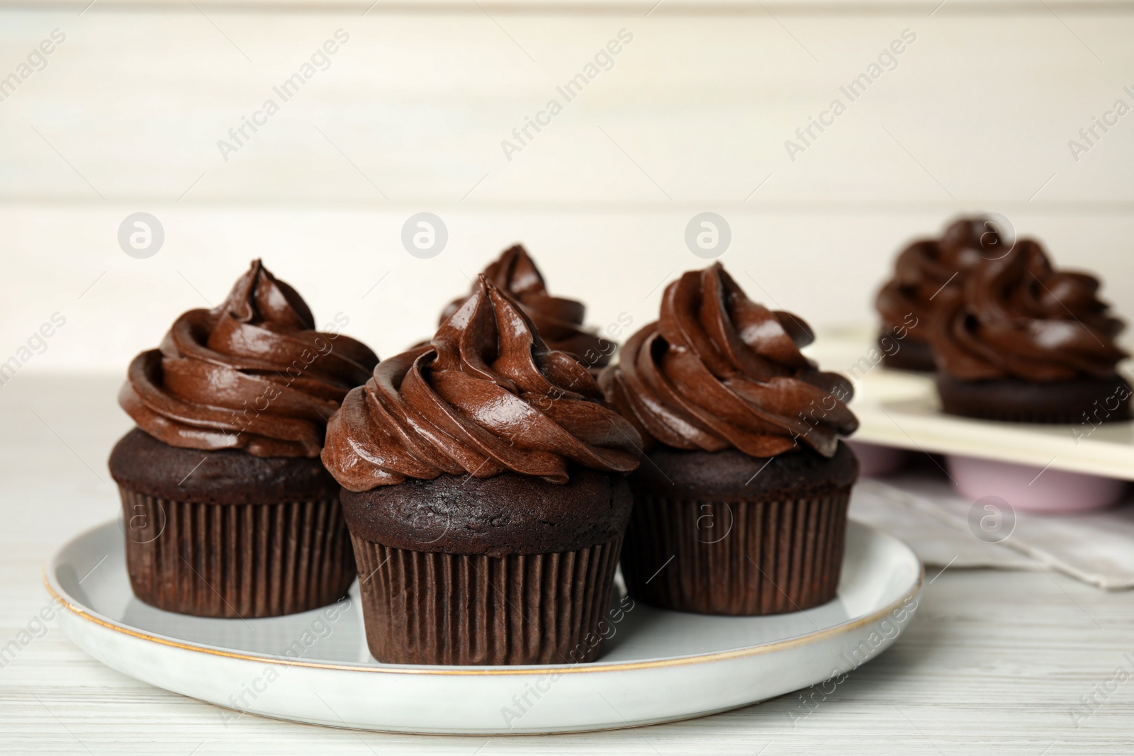 Photo of Plate with delicious chocolate cupcakes on white wooden table