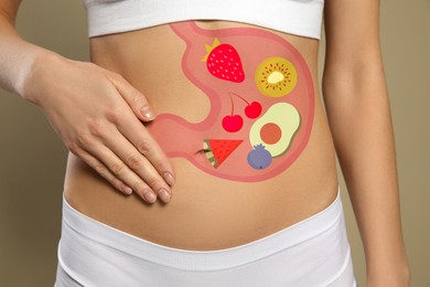 Image of Woman with image of stomach full of food drawn on her belly against beige background, closeup. Healthy eating habits