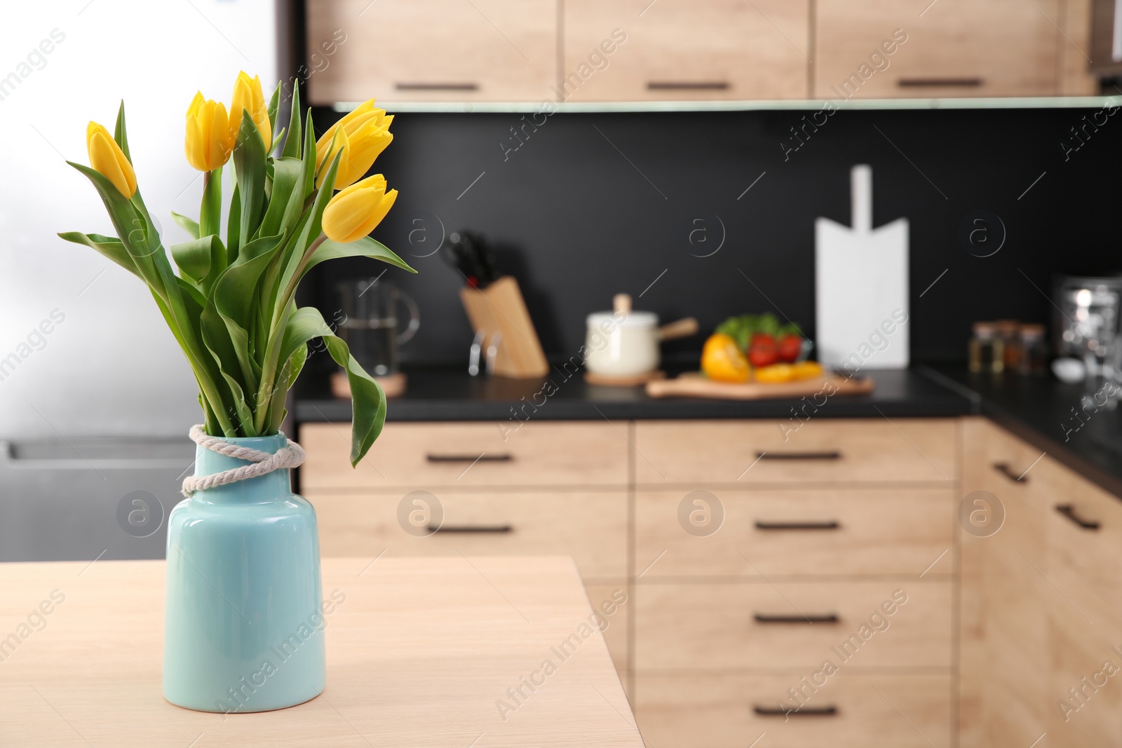 Photo of Ceramic vase with tulips on table in kitchen