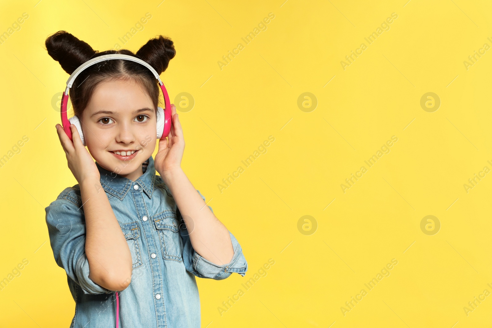 Photo of Cute girl enjoying music in headphones on color background. Space for text