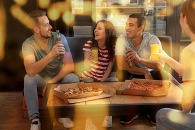 Group of friends having fun party with delicious pizza in cafe, bokeh effect