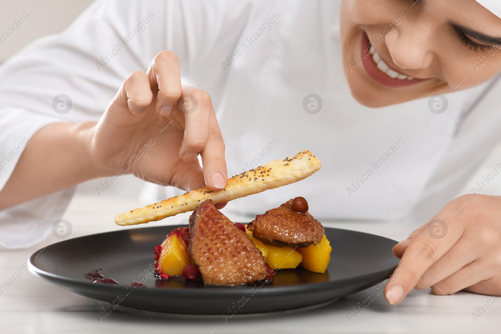 Photo of Professional chef decorating delicious dish with crispy bread at marble table, closeup