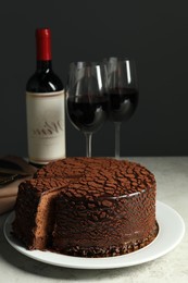 Photo of Delicious chocolate truffle cake and red wine on grey table