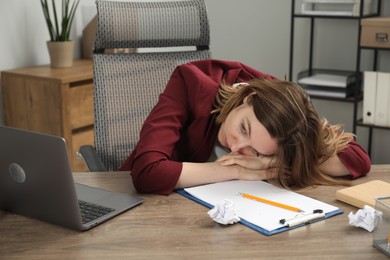 Sad businesswoman working at wooden table in office