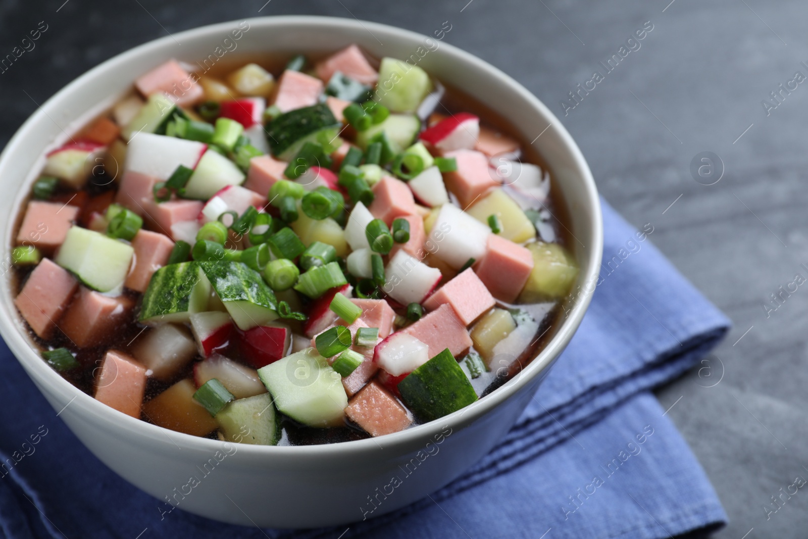 Photo of Delicious cold okroshka with kvass on black table, closeup. Traditional Russian summer soup