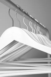 Photo of White clothes hangers on metal rail against light background, closeup
