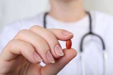 Photo of Doctor holding red pill, closeup. Anemia concept