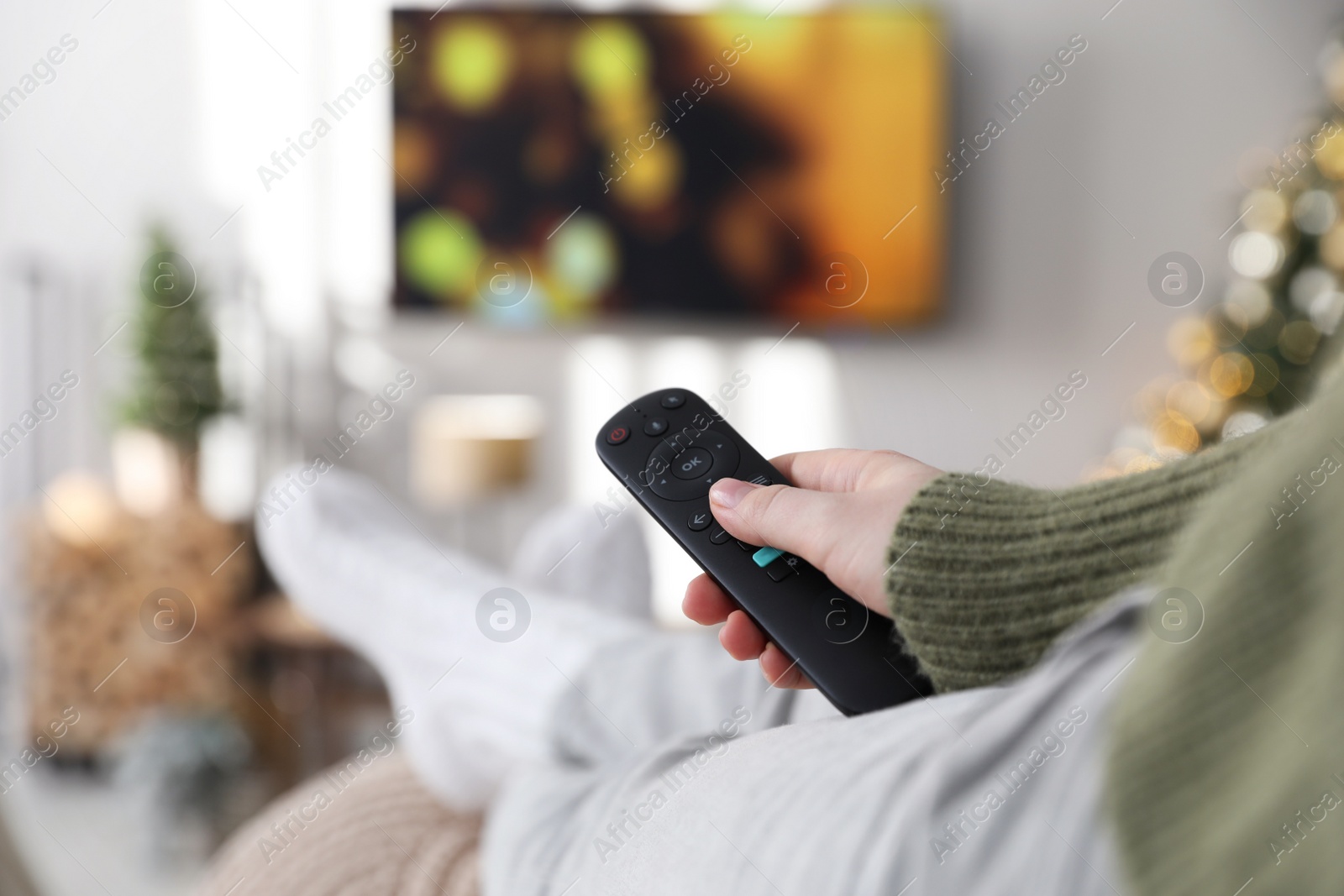 Photo of Woman with remote control in room decorated for Christmas, closeup