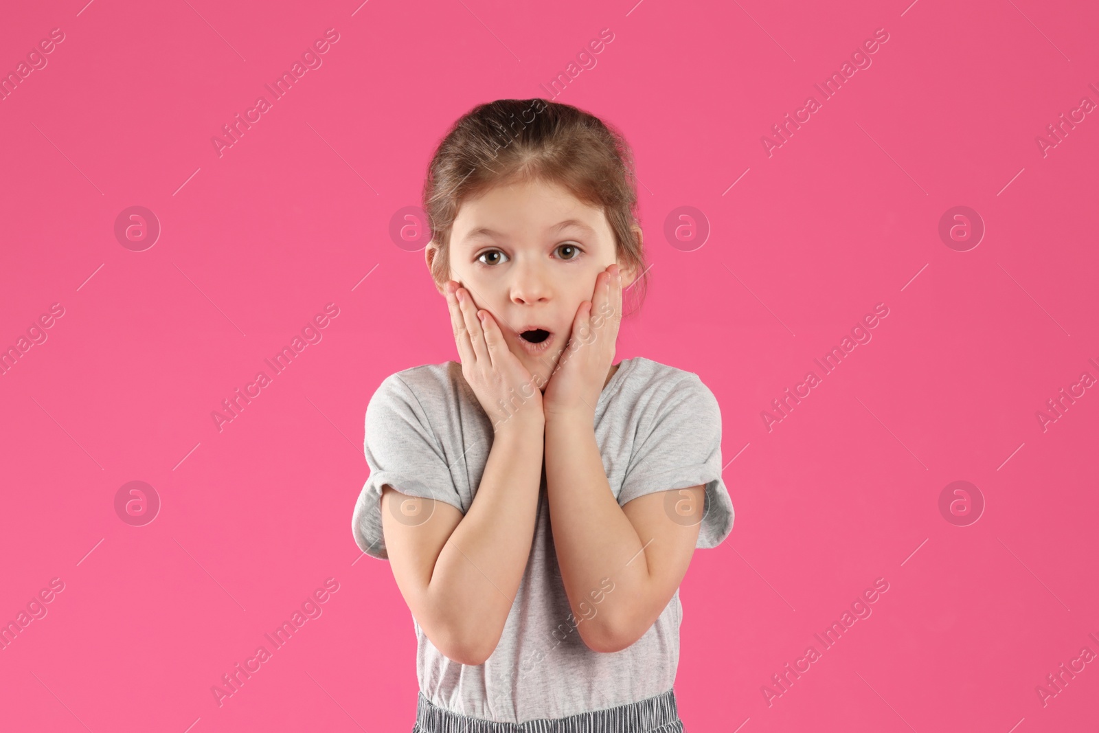 Photo of Portrait of shocked little girl on pink background