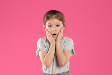 Photo of Portrait of shocked little girl on pink background