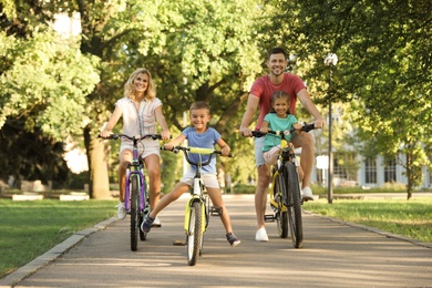 Photo of Happy family with children riding bicycles in park