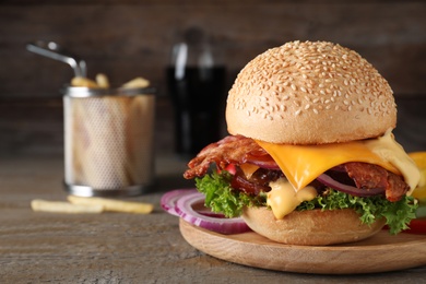 Photo of Composition with juicy bacon burger on wooden table. Space for text