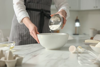 Woman making dough at table in kitchen, closeup