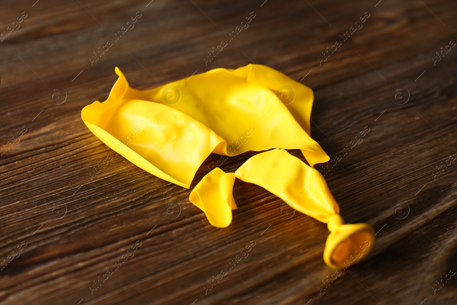 Photo of Popped yellow latex balloon on wooden background