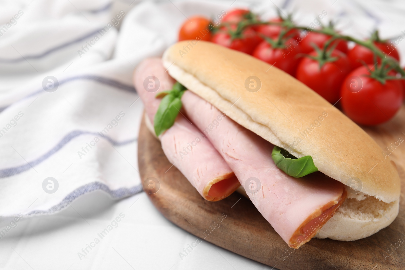 Photo of Delicious sandwich with ham and basil on white table, closeup. Space for text