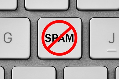 Prohibition sign with word Spam on laptop button, top view. Device keyboard, closeup