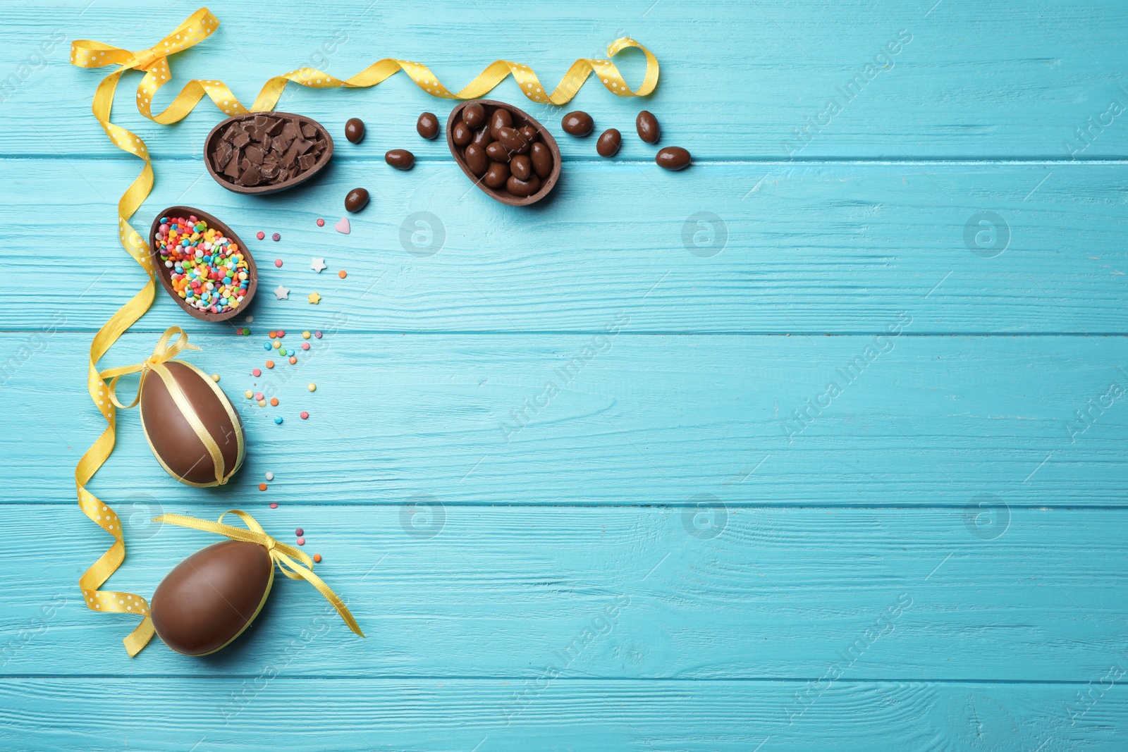 Photo of Frame made of chocolate Easter eggs on color wooden background, top view with space for text