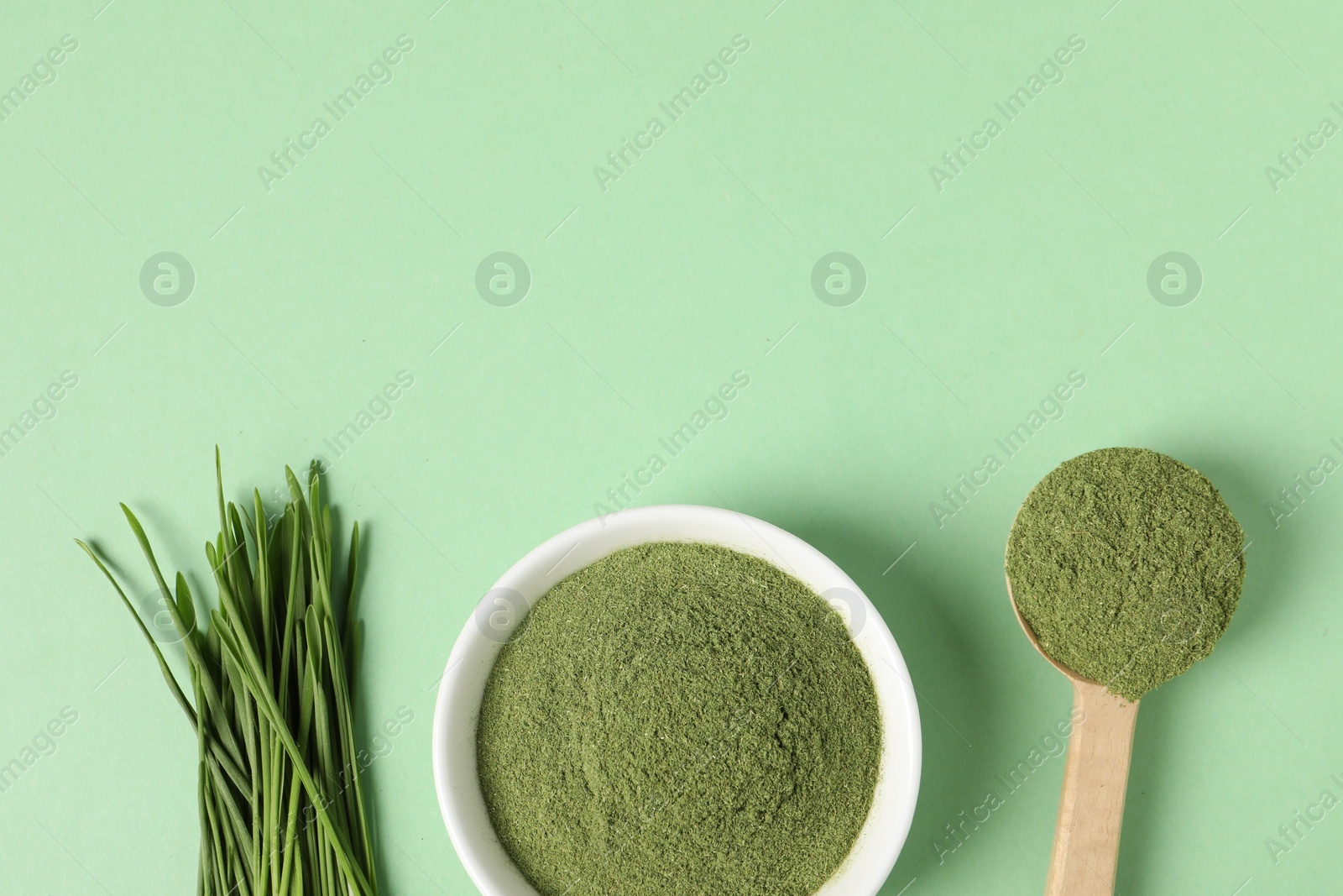 Photo of Wheat grass powder and fresh sprouts on green table, flat lay. Space for text