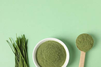 Wheat grass powder and fresh sprouts on green table, flat lay. Space for text