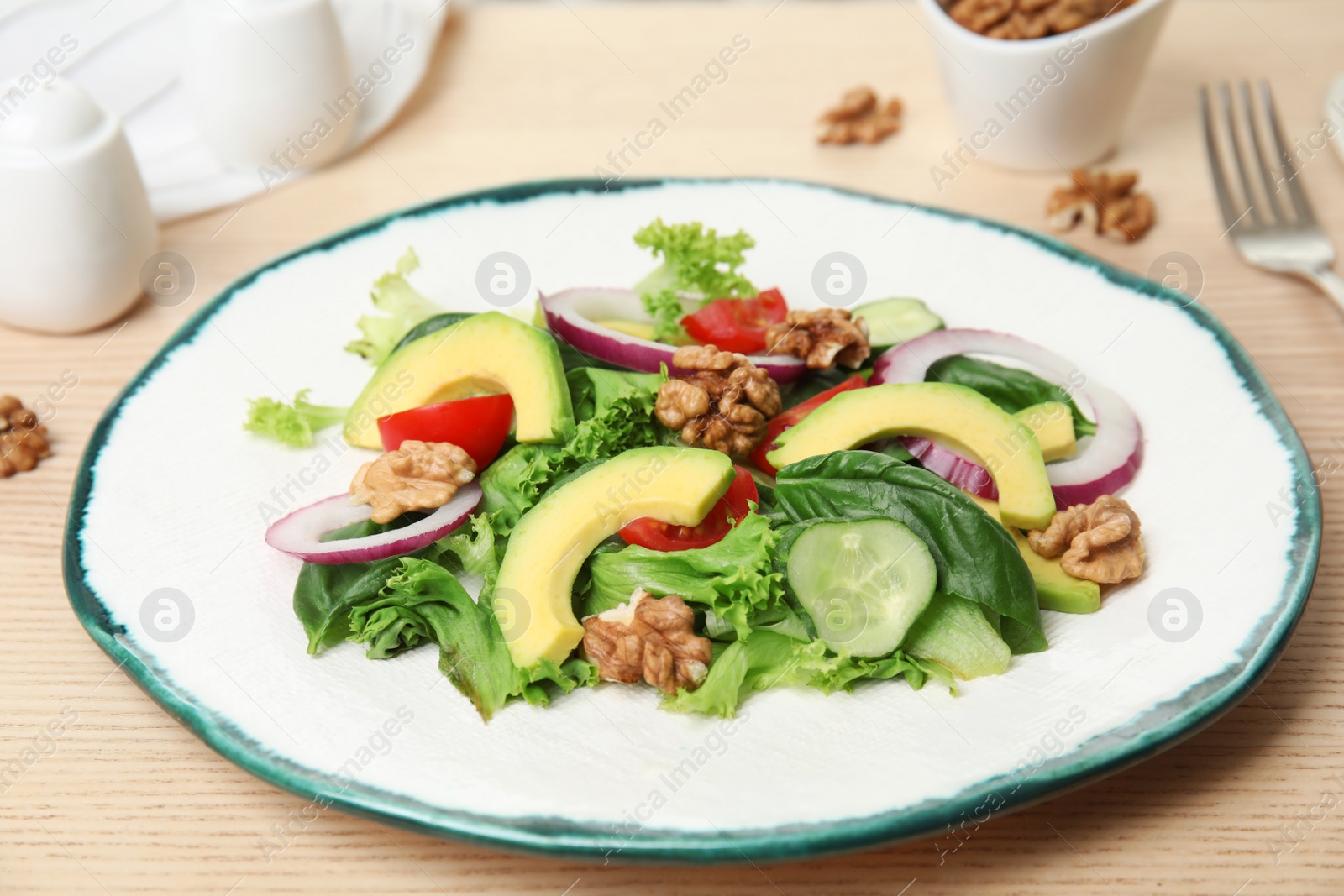 Photo of Delicious avocado salad with walnuts on wooden table