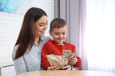 Happy mother and son with money at home