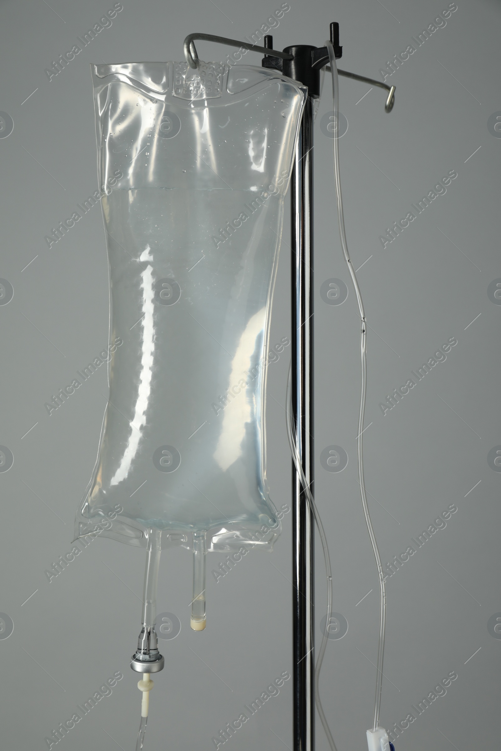 Photo of IV infusion set on pole against grey background, closeup