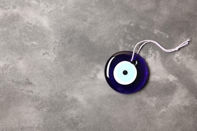 Photo of Evil eye amulet on grey table, top view. Space for text