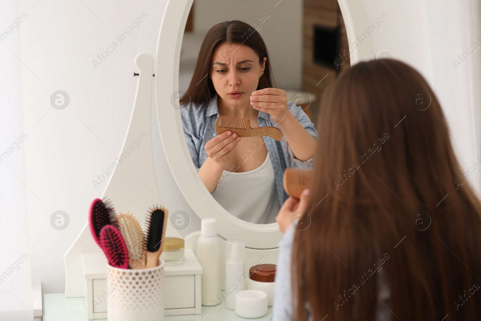 Photo of Emotional woman with hair loss problem near mirror indoors