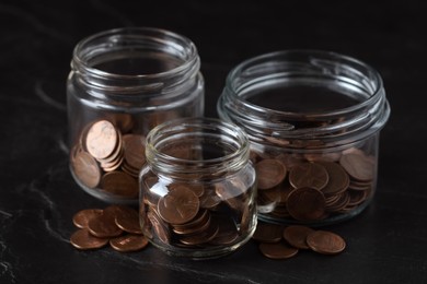 Photo of Glass jars with coins on black marble table