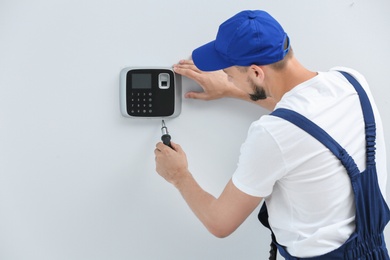 Photo of Young male technician installing alarm system indoors