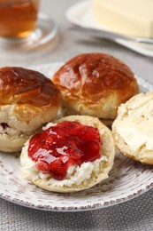 Photo of Freshly baked soda water scones with cranberry jam and butter on light grey mat, closeup