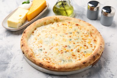 Photo of Delicious cheese pizza, oil and different kinds of cheese on light grey textured table