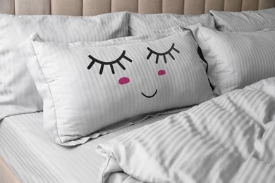 Image of Soft pillow with cute face on comfortable bed 