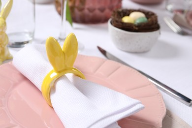 Photo of Festive table setting with napkin ring in shape of bunny ears, closeup. Easter celebration