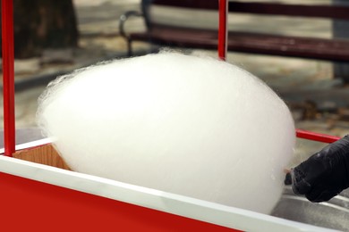 Man making cotton candy with machine outdoors, closeup