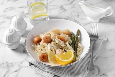 Photo of Delicious scallop pasta served on white marble table