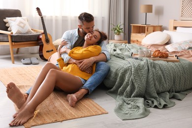 Lovely couple enjoying time together on floor in bedroom