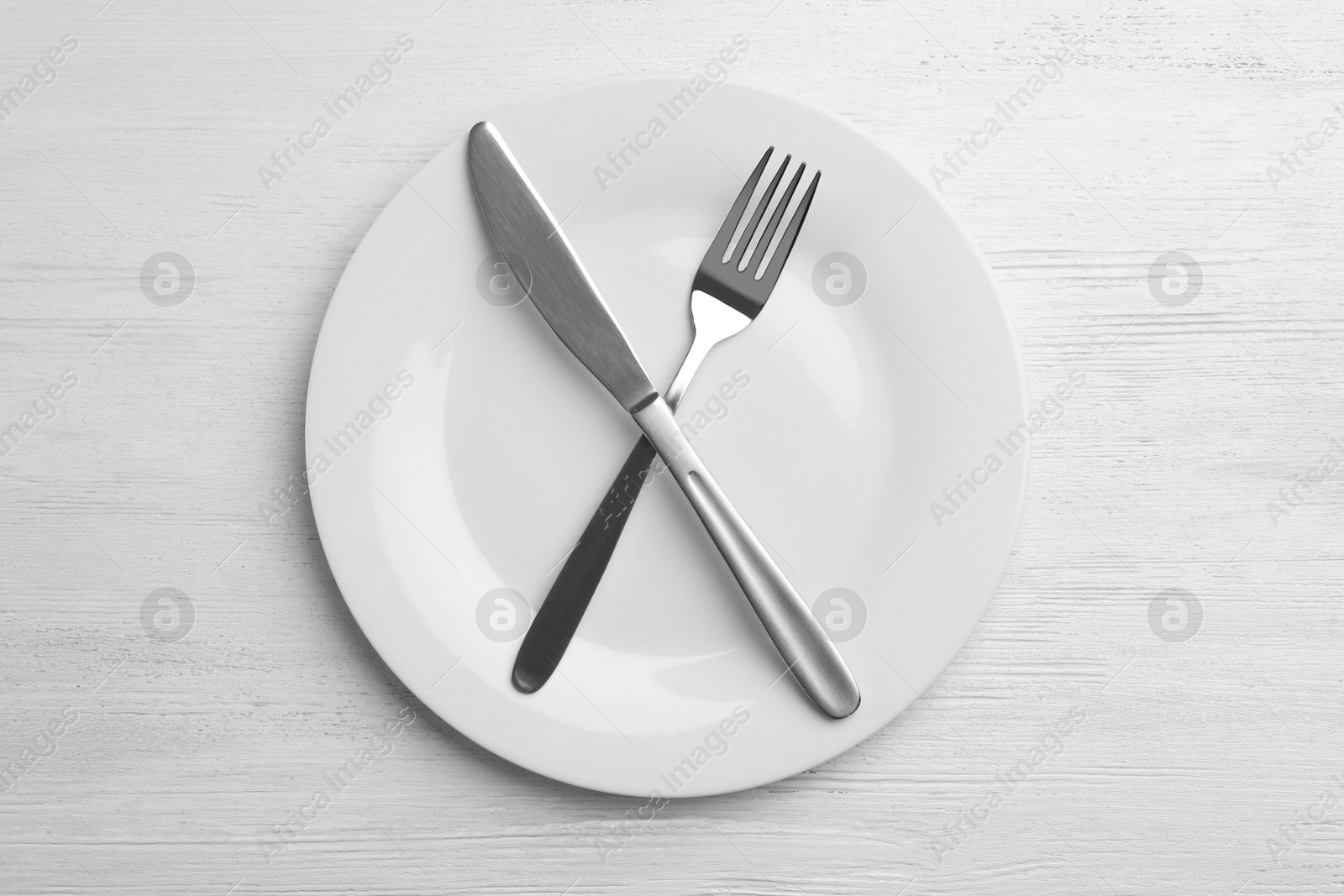 Photo of Empty plate with cutlery on white wooden background, flat lay