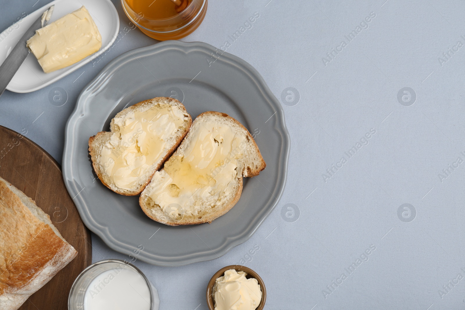 Photo of Sandwiches with butter, honey and milk on light grey table, flat lay. Space for text