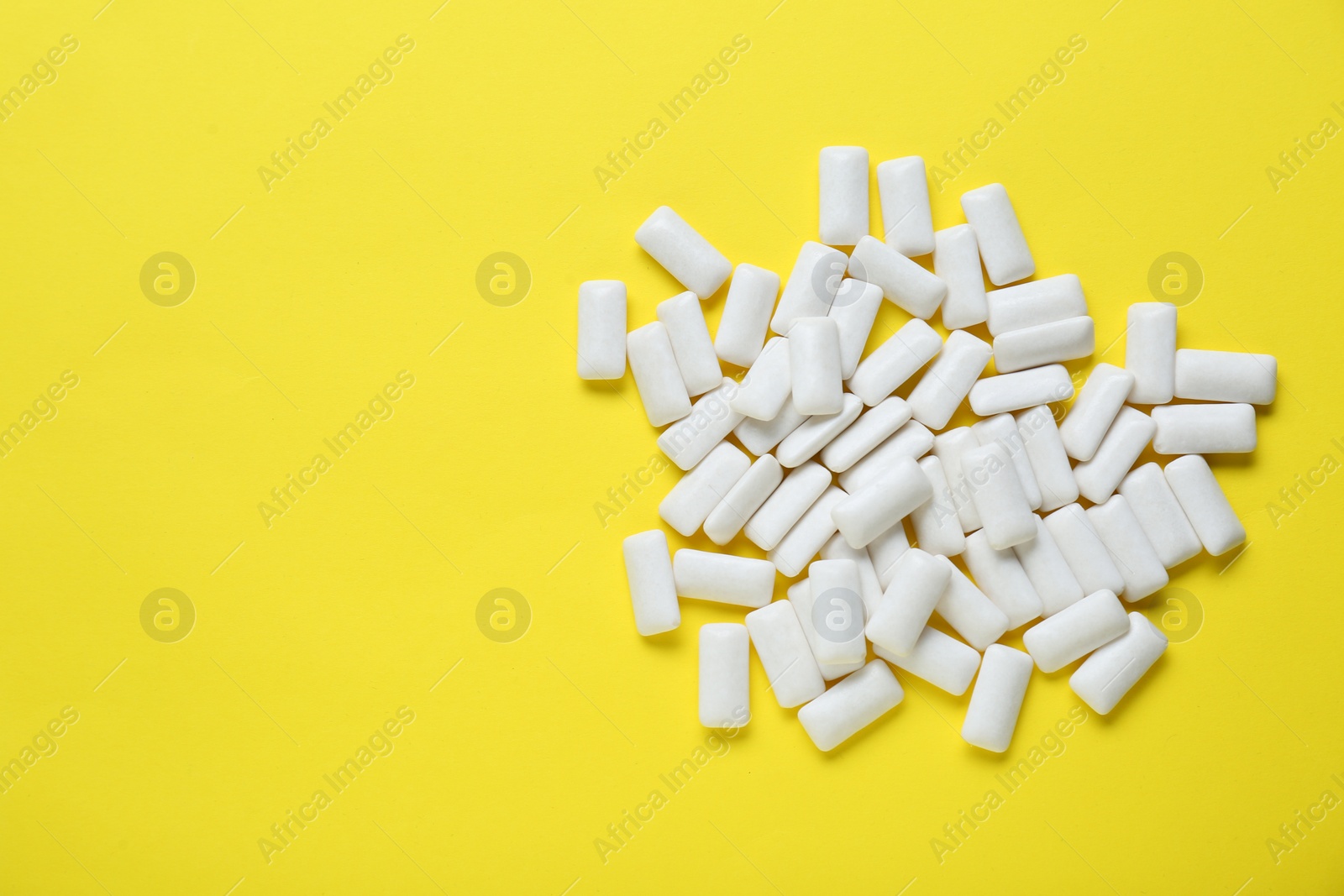 Photo of Tasty white chewing gums on yellow background, flat lay. Space for text