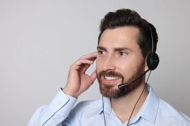 Photo of Hotline operator with headset on light grey background, space for text
