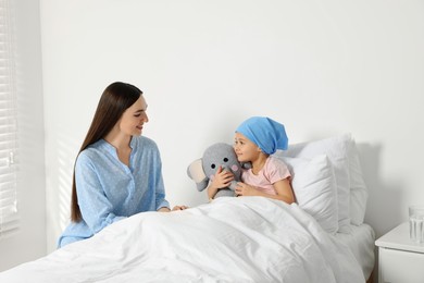 Childhood cancer. Mother and daughter with toy elephant in hospital