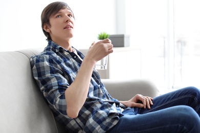 Photo of Portrait of young man drinking water on sofa