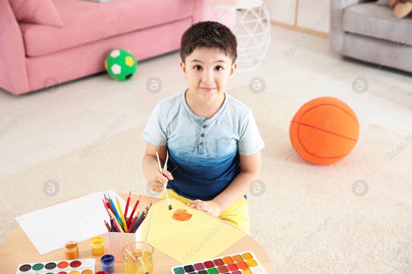 Photo of Cute little child painting at table in playing room