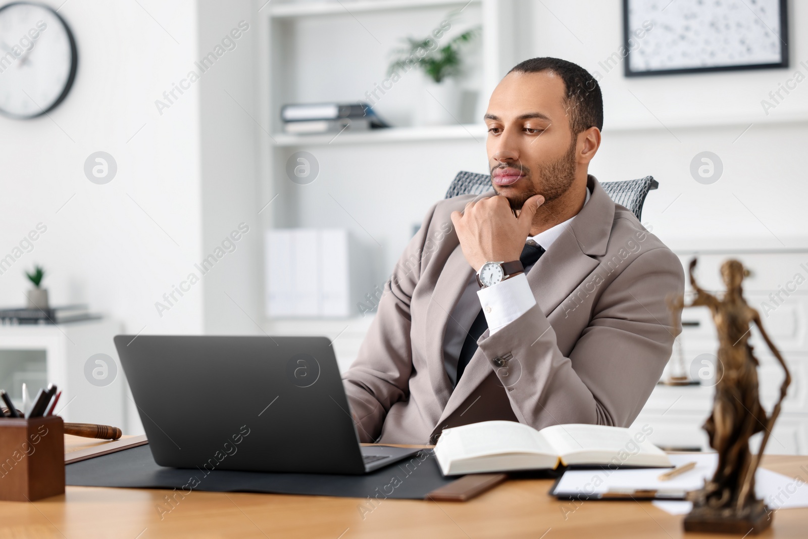 Photo of Serious lawyer working with laptop at table in office