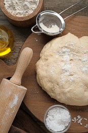 Fresh yeast dough and ingredients on wooden table, flat lay