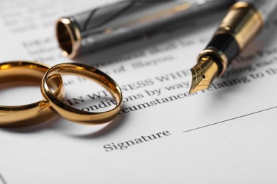 Marriage contract, gold rings and pen on table, closeup