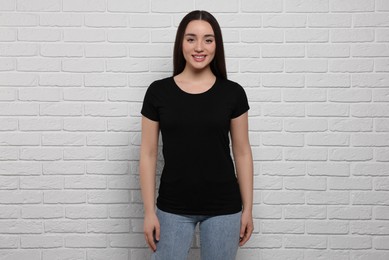 Woman wearing stylish black T-shirt near white brick wall