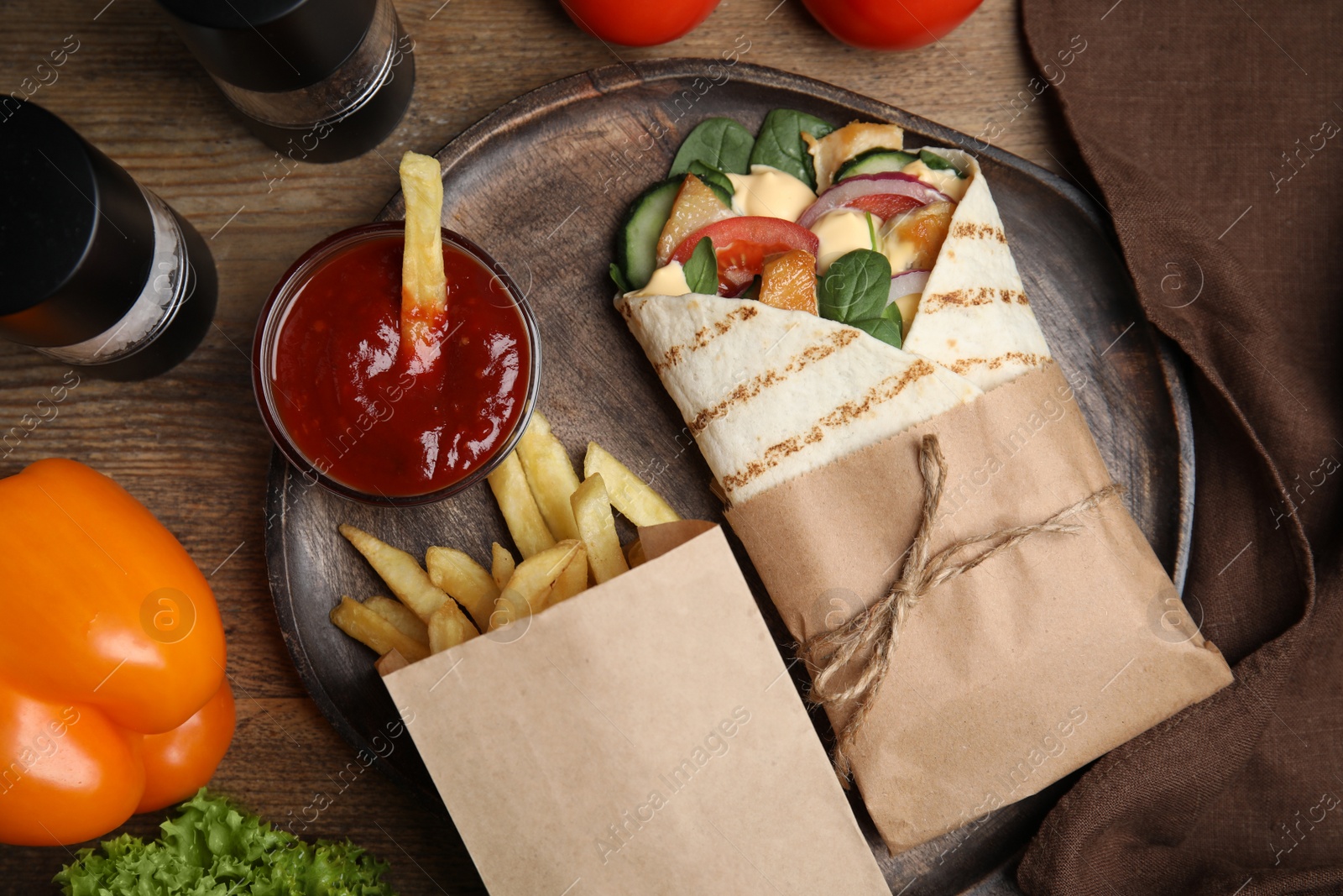 Photo of Delicious chicken shawarma and French fries served on wooden table, flat lay