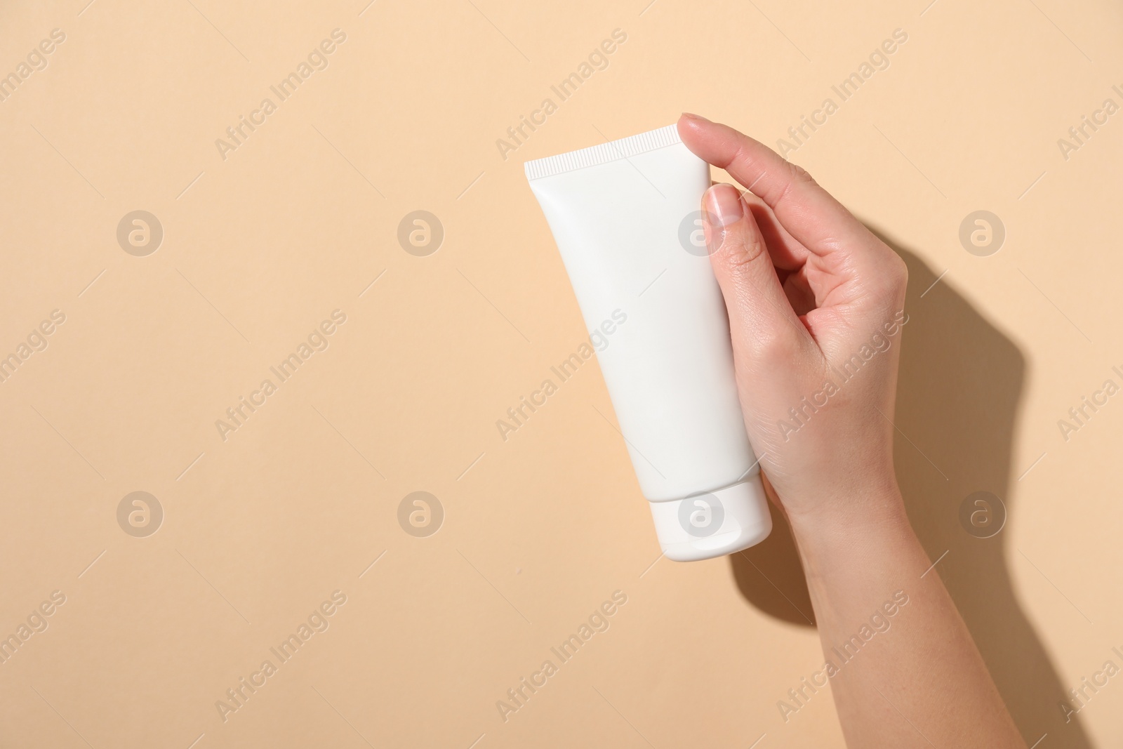 Photo of Woman with tube of hand cream on beige background, top view. Space for text